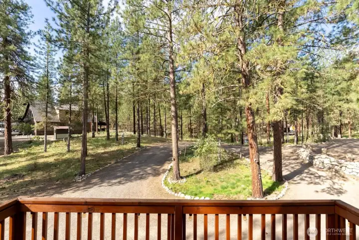 Primary balcony opens to entrance loop driveway and treed landscape