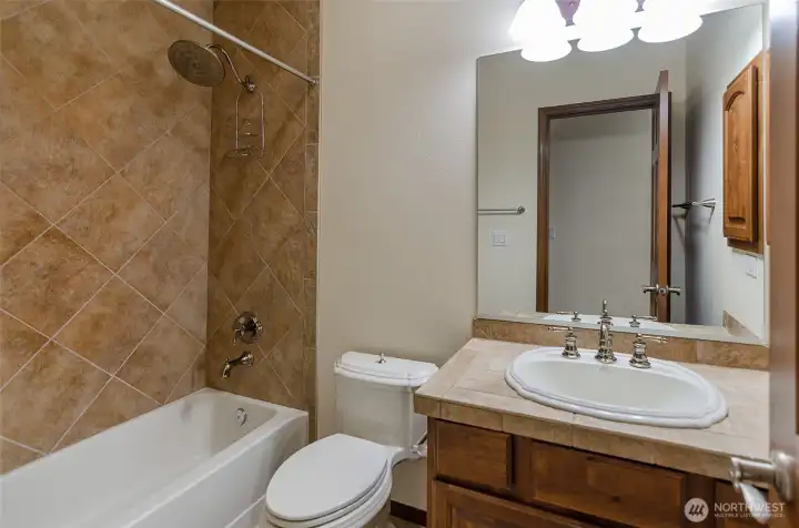 Hall bath with full tile tub surround.