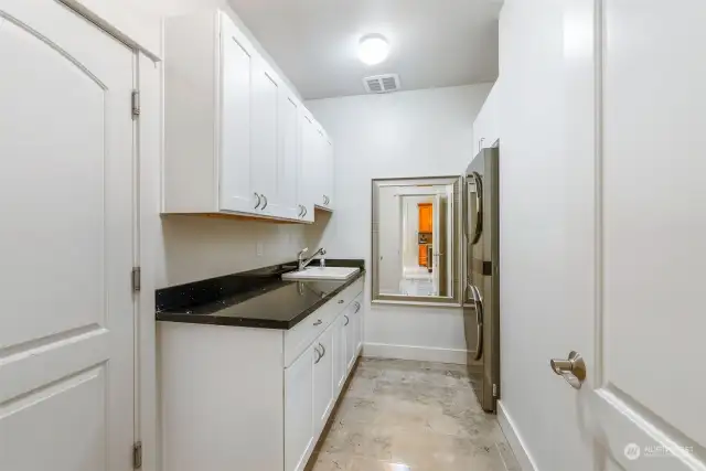 Spacious laundry room on the main floor. The location is near the front door to the left and has an entrance to the 2 car garage.