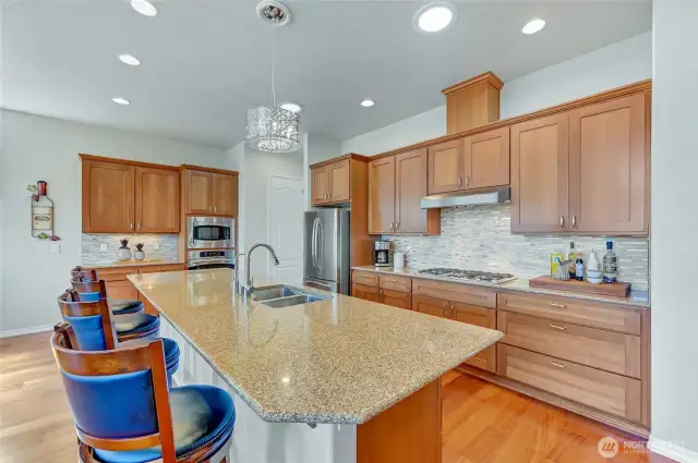 The kitchen area has 42" upper cabinets, under cabinet lighting, lower cabinets with pull-out shelves, updated tile backsplash and a huge slab granite island with seating.