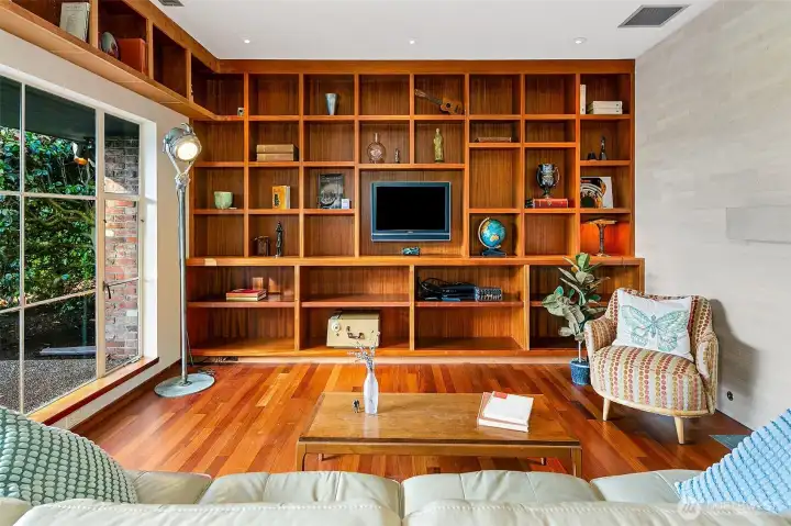 Handcrafted mahogany casework anchors the Great Room and showcases the level of craft carried through the home. African mahogany flooring adds warmth underfoot while the custom metal fireplace screen, designed by the project artisan, brings a sculptural note to this finely made space.