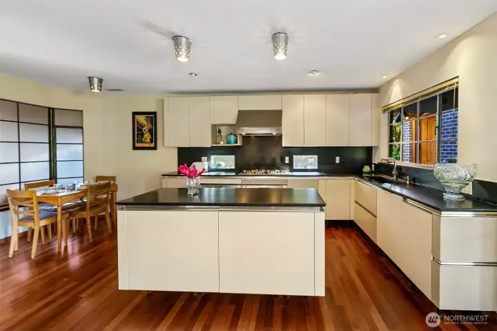 The Snaidero kitchen, designed by Renzo Piano, reflects the clarity and craft seen in his architectural work on the Centre Pompidou in Paris, the Menil Collection in Houston and the Whitney Museum expansion in New York. Sleek Italian cabinetry pairs with honed black-granite counters and custom metal detailing around the ventilation system. Dual Gaggenau convection ovens, a Smeg electric cooktop with downdraft vent and integrated Thermador refrigeration form a modern, efficient work zone set against radiant mahogany floors and natural light.