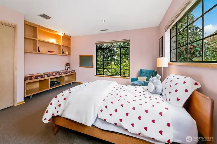 The Fairway Bedroom features custom mahogany built-ins and a large steel window that frames the treetops and landscaped grounds. Merino wool carpeting adds warmth while the quiet detailing and natural light give this room a calm, crafted character.