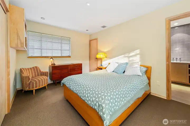 The guest bedroom features custom built-ins, warm wood detailing and Merino wool carpeting. Soft natural light and simple, well-made finishes give this room a quiet, welcoming character with a clear view toward the en suite bath.