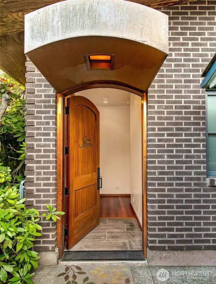 A curved canopy and brick surround frame the bungalow’s solid-cedar arched door, creating a sheltered threshold that feels both crafted and intentional. The design quietly signals the level of detail found throughout the structure, setting the tone for the residence’s standalone character and privacy.