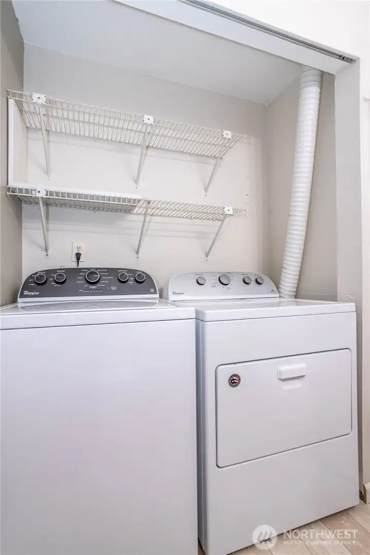 Laundry area with built-in shelving and side-by-side washer and dryer.