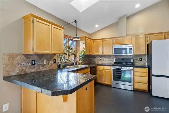 Kitchen boasts granite tile counters, eating bar, SS appliances, & skylights.