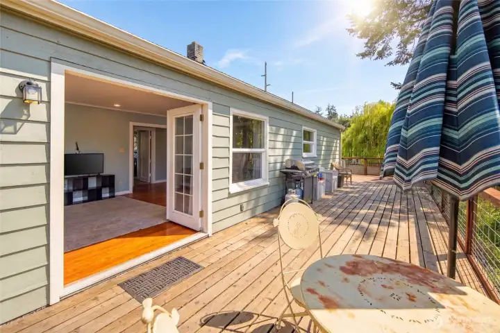 A classic French door opens seamlessly from the bright living area onto the generously sized back deck, creating effortless indoor-outdoor living and al fresco dining space overlooking the fenced yard. The deck's elevated vantage point and mature weeping willow backdrop make this an exceptional outdoor retreat.