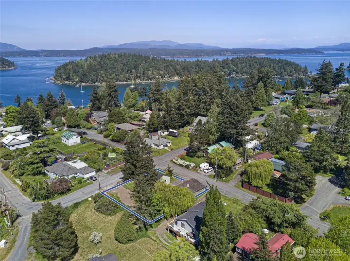 The generous 0.24-acre corner lot is clearly defined in this aerial view, showcasing its advantageous multi-family zoning potential and easy access from two street frontages, with sparkling San Juan Channel waters visible in the background.