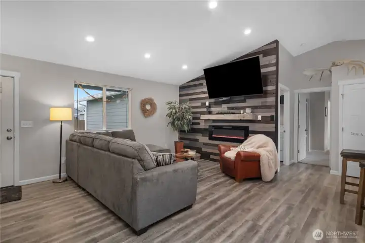 Gather in the great room with vaulted ceilings, recessed lighting, durable flooring, and a stylish feature wall.