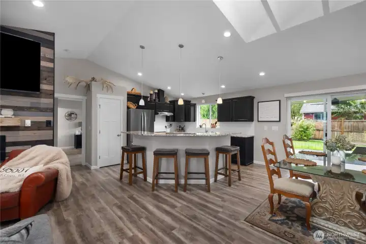 Entertain with ease in the open kitchen and dining area featuring island seating, stainless appliances, and covered patio access.