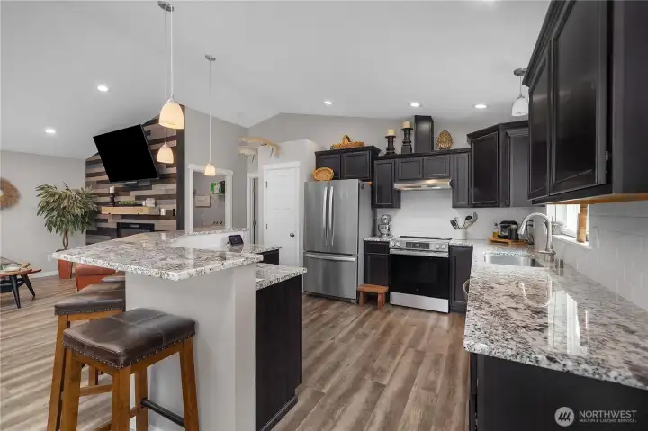 Cook and gather in the stone and stainless kitchen with island seating, pendant lighting, and an easy connection to the great room.