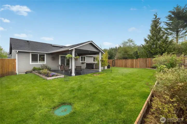 Enjoy the landscaped, fenced backyard with lawn space, garden beds, and a covered patio for easy outdoor living.