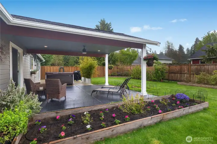 Entertain or relax on the covered patio overlooking the fenced yard, garden beds, and mature plantings.
