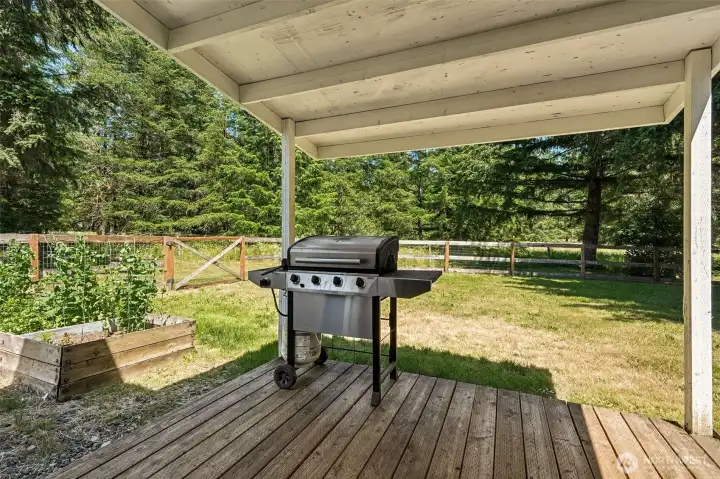 One of the joys of country living is how naturally the indoors and outdoors come together, and this covered porch captures that beautifully. Located just outside the sliding glass doors and only a few steps from the raised gardens, this space makes it easy to enjoy the harvest right outside your door. Fresh herbs for dinner? A quick stroll away. Morning coffee while listening to the birds? You've found the perfect spot. The covered roof means the weather doesn't get to decide whether you're grilling dinner or enjoying an evening outdoors. Surrounded by the beauty of the property and overlooking the thoughtfully designed garden spaces, this porch is the kind of everyday luxury that quickly becomes your favorite place to unwind.