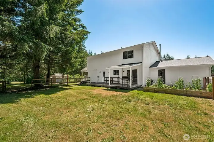 The covered porch extends naturally into an open deck, giving you the best of both worlds: a sheltered space for year-round barbecues and outdoor dining, plus an uncovered area that's perfect for soaking up a little Pacific Northwest sunshine. Just beyond, you'll notice the extra-long raised garden bed leading toward the private entrance of the bonus room, making it easy to surround the home with flowers, herbs, or your favorite seasonal vegetables. The backyard is fully fenced, with one gate currently awaiting a little TLC, offering the next owner a simple project to complete. You'll also appreciate the gravity-fed septic system, which operates without the need for a pump, resulting in fewer mechanical components to maintain and one less system requiring electricity.