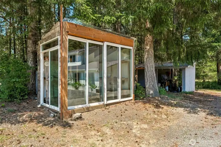Every great acreage seems to collect a few wonderful surprises, and this charming greenhouse shed is definitely one of them. Filled with natural light, it has the feel of a cozy little garden atrium where seedlings can get an early start, potted plants can overwinter, or you can simply enjoy a peaceful place surrounded by greenery. Nearby you'll also find an outdoor sink station already in place, ready for a future owner to hook up and put to work after a day in the garden. With abundant RV and boat parking, multiple outbuildings, and even a dedicated firepit gathering area elsewhere on the property, this is an estate that's designed to be enjoyed. Every structure adds another layer of function and charm, creating a property that feels thoughtfully assembled over time.