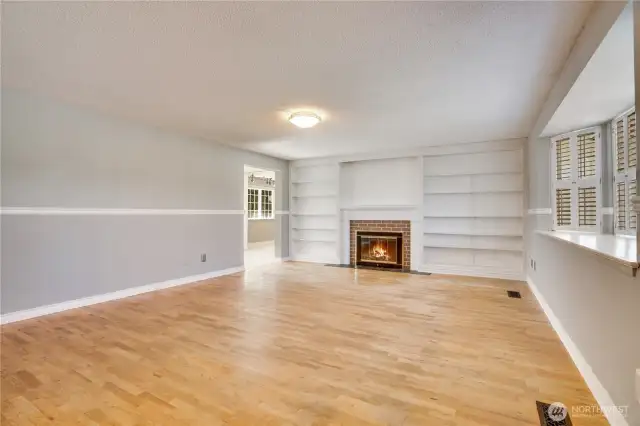 Hardwoods throughout main living area. Built in bookshelves, chair rail, updated windows, and gas fireplace at center.