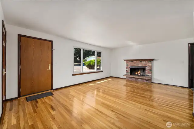 The welcoming living area features a solid wood front door, refinished hardwoods, and a brick fireplace that anchors the room. Enjoy a quiet retreat thanks to the quadruple-pane windows, designed for both comfort and efficiency.