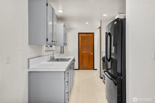 Practical layout with direct access to the laundry room, keeping household chores convenient and tucked away. Modern recessed lighting brightens the space, while painted cabinets offer a timeless, clean look.