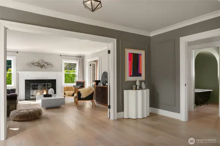 From the foyer, sightlines open into the sunlit living room where wide-plank oak floors lead to a striking soapstone-surround fireplace.