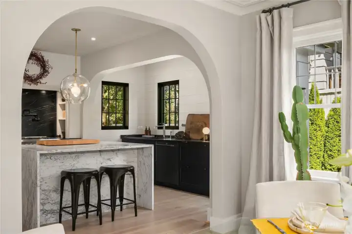 A Carrera marble island with integrated Bocci outlets pairs beautifully with soapstone stove backsplash and sink countertops.