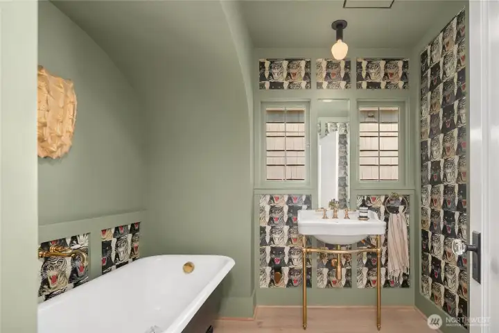 Gucci wallpaper and a custom painted claw-foot tub bring playful sophistication to this exquisite first floor bathroom. Waterworks fixtures and brass detailing complete the perfect balance of bold design and timeless quality.