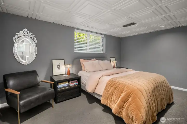 The second of two ADU bedrooms presents a moody, modern retreat with plush carpeting, bold wall color, and space for both rest and reading.