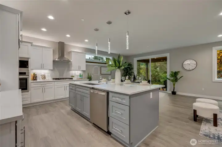 The heart of this home, a modern chef’s kitchen dazzles with pristine quartz countertops, top-of-the-line stainless steel appliances, and an abundance of custom cabinetry — blending exquisite design with effortless functionality.