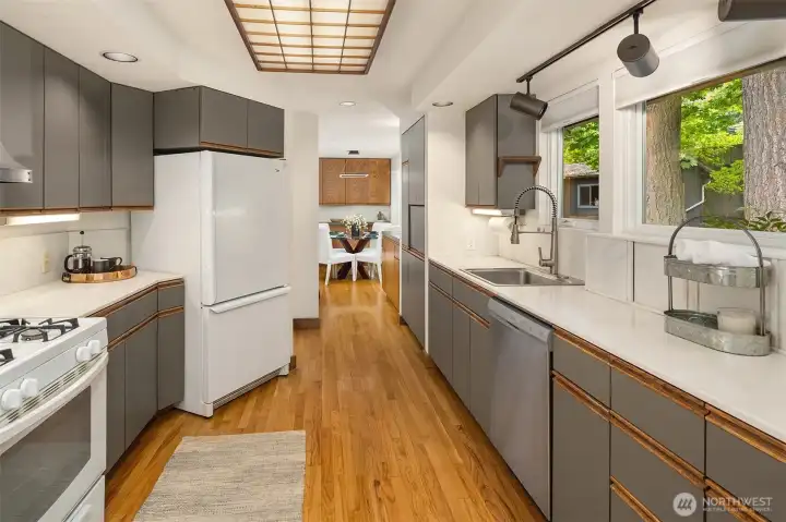 Spacious galley kitchen with an abundance of cabinets, hardwood floors and gas range.