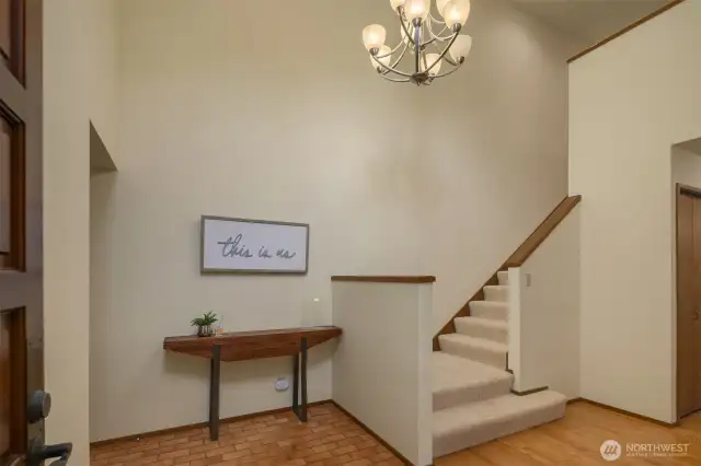 The front door is shown to the left, and beyond that to the left is the entry from the garage. Bright and cheery tiled entry with high ceilings and lots of light.