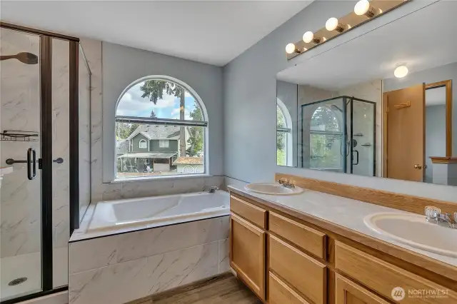 The remodeled primary bathroom has beautiful tile, double sinks, a separate shower, and a Jacuzzi tub.