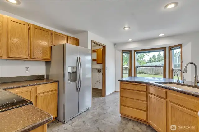 Here you'll see the cabinets, Corian countertops and stainless steel refrigerator. The nook is just past the countertop and the utility room with storage is just through the doorway.