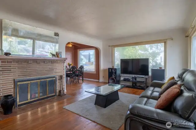 The spacious living room with its wood burning fireplace and original hardware floors are the great foundation showing the potential of this home.