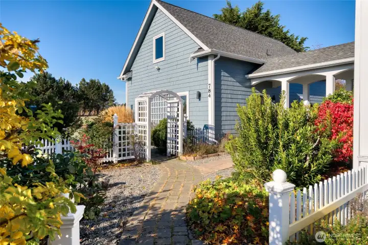 A grape trellis and blooming lavender line the garage.