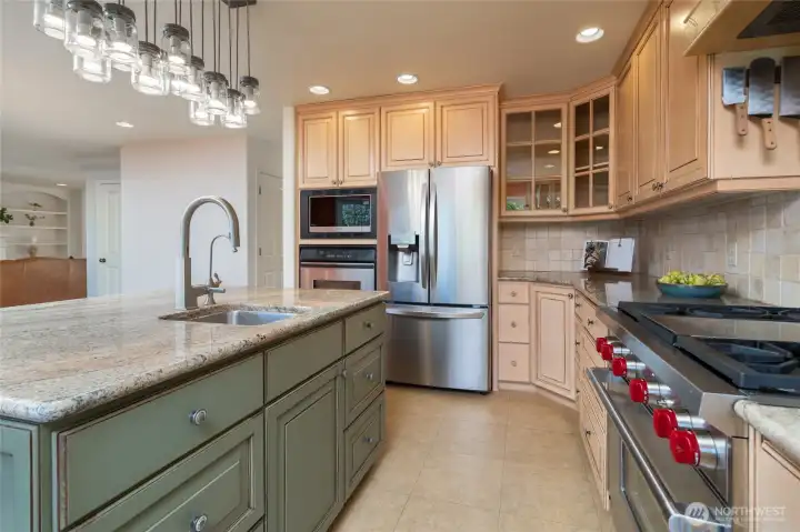 Gourmet kitchen with Wolf oven and a spacious island offering a second sink, separate water filter, and breakfast bar, all connected to the open great room.