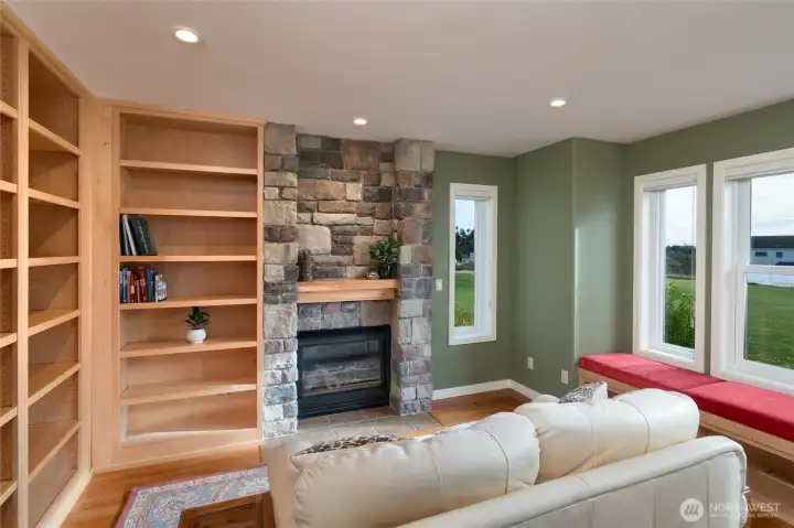Library with fireplace, window seat, and floor-to-ceiling maple built-in bookshelves with entertainment space.