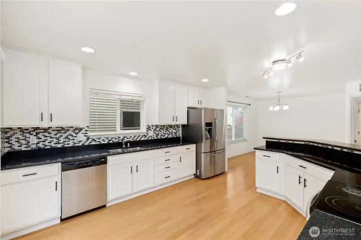 The kitchen is sunlit, airy. Perfect for family gathering at eating space. Granite countertop, tiled backsplash, SS appliances, hardwood floor.