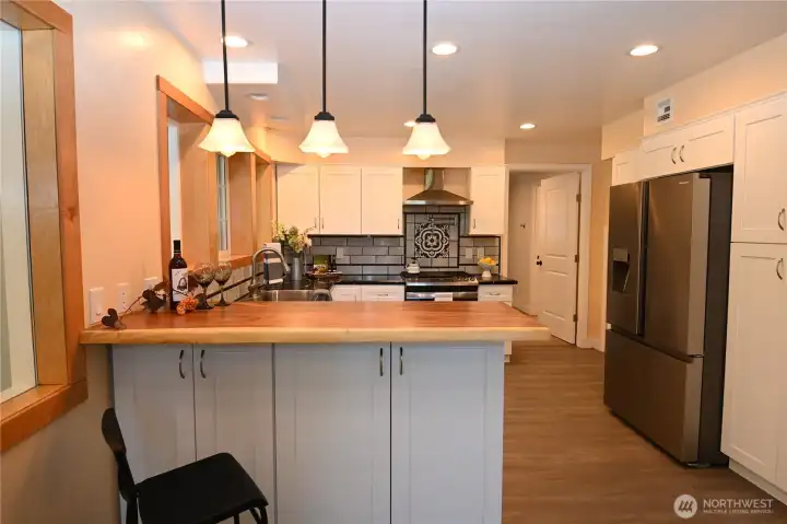 Crisp white cabinetry complements the home's design elements, beautifully paired with rich acacia bar seating.