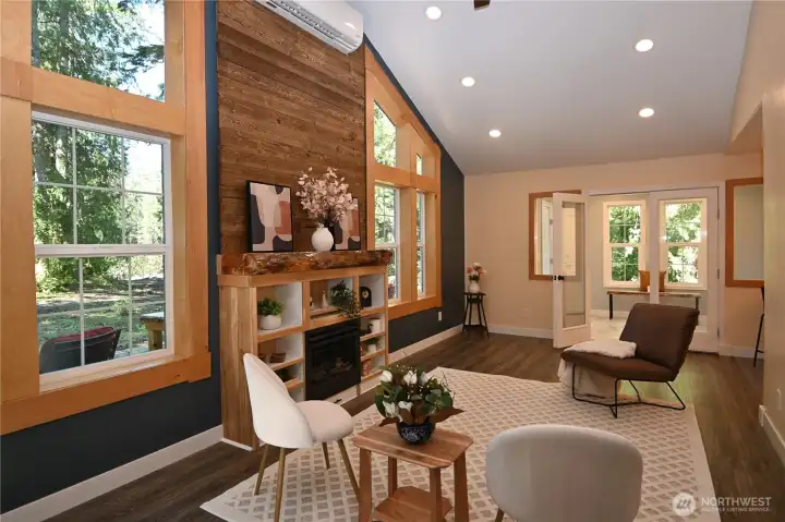 Vaulted ceilings soar above a gas fireplace with custom wood mantel, wrapped windows, and a warm floor-to-ceiling wood wall feature ~ crafted from timber sourced on the property ~ create a true standout living space.