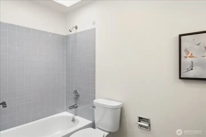 Brightened by an overhead skylight, the en-suite bath offers a clean, fresh retreat for both quick mornings and relaxed evenings.
