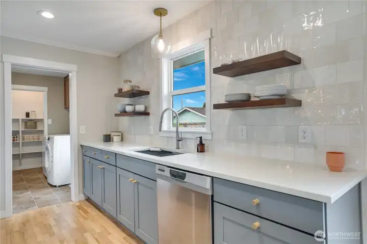The kitchen flows seamlessly into the mudroom and laundry area, complete with stairs to the upstairs bedroom, additional storage closets, a walk-in pantry, and convenient access to the outdoors.