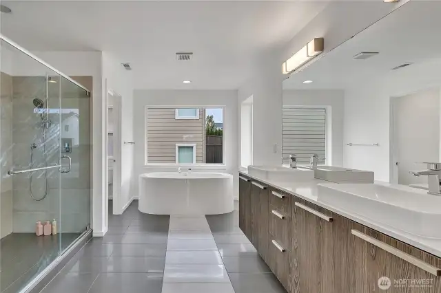 A glorious 5-piece bath with full height tile surround, double vanity, soaking tub, and toilet room.