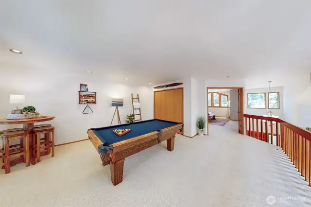 Upstairs game room. Doors to the right lead to the large primary suite. The pool table, mounted racks, pool cues, supplies and decorative wooden propeller included in the sale.