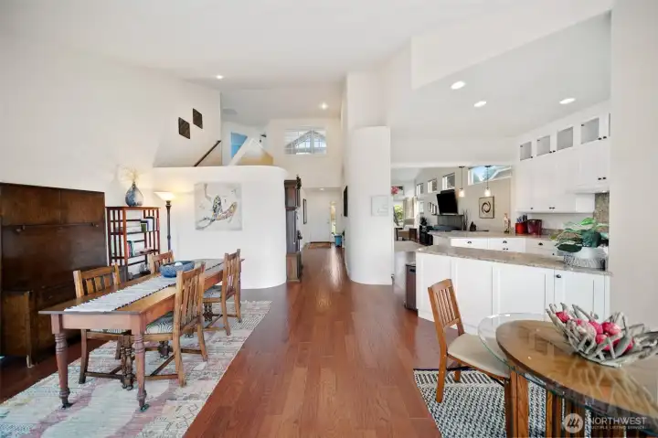 This perspective from the rear of the home showcases the soaring cathedral ceilings, seamless flow of spaces, and stunning hardwood floors.