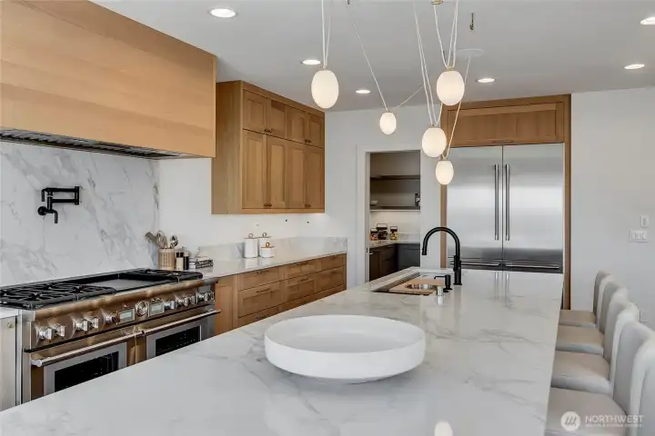 The kitchen features an oversized slab-quartz island and a full suite of premium appliances. It offers two dishwashers, two sinks, two disposals, double ovens and refrigerator drawers for effortless cooking and entertaining.