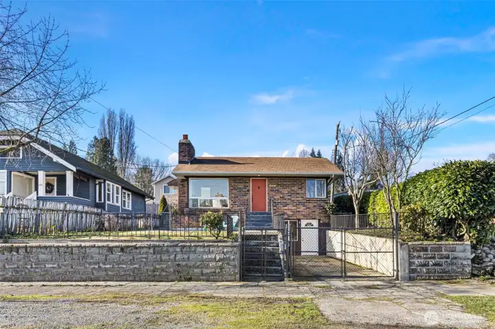 Gated front drive and mature plantings frame the home, balancing openness with a sense of separation from the street.