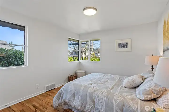 The front bedroom is the most generously sized in the home, with corner windows facing east and north plus an additional north-facing window for consistent natural light.