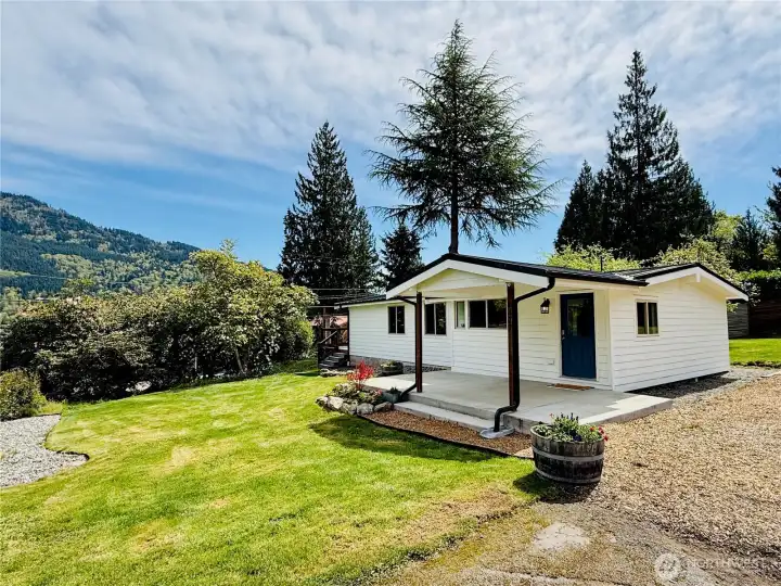 A large, covered concrete patio is adjacent to the parking area.