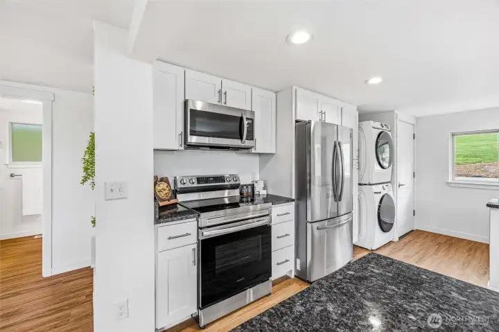 Stainless steel appliances plus a stacked washer and dryer.